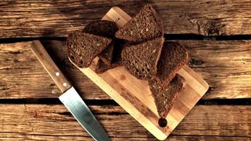 Super slow motion pieces of fragrant bread fall on the cutting board.Filmed on a high-speed camera at 1000 fps. On a wooden background. Top view video