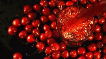 Super slow motion cherry juice pours into the glass with spray. On a black background. Top view.Filmed on a high-speed camera at 1000 fps. video