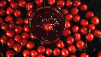 Super slow motion in a glass with juice falls ripe cherry with splashes. On a black background. Top view.Filmed on a high-speed camera at 1000 fps. video