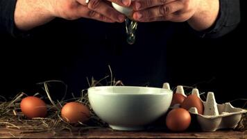 Super slow motion male hands smash raw egg into the bowl. On a black background. Filmed on a high-speed camera at 1000 fps. video