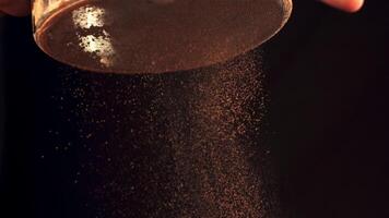 Super slow motion cocoa powder is poured through a sieve. On a black background. Filmed on a high-speed camera at 1000 fps. video