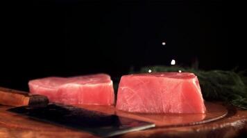 Super schleppend Bewegung auf roh Thunfisch Steaks Tropfen Salz. auf ein schwarz Hintergrund. gefilmt auf ein schnelle Geschwindigkeit Kamera beim 1000 fps. video