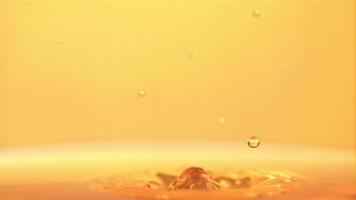 The super slow motion drop falls into the apple juice with splashes. On a yellow background. Filmed on a high-speed camera at 1000 fps. High quality FullHD footage video