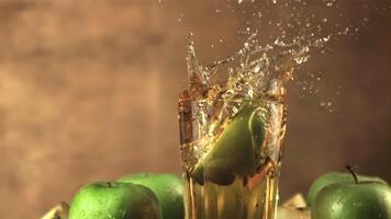 Super slow motion a piece of fresh apple with splashes falls into a glass of juice. On a brown background.Filmed on a high-speed camera at 1000 fps. video