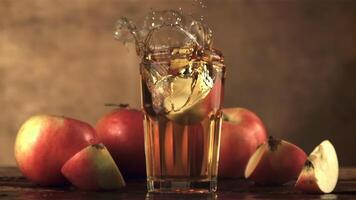 Super slow motion in a glass with apple juice falls a piece of apple with spray. On a brown background.Filmed on a high-speed camera at 1000 fps. video