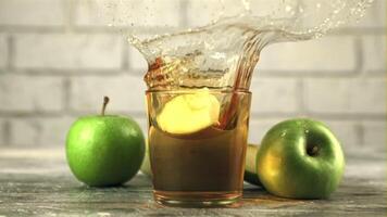 súper lento movimiento en un vaso con manzana jugo gotas un pedazo de manzana con salpicaduras en un blanco antecedentes. filmado en un alta velocidad cámara a 1000 fps. video