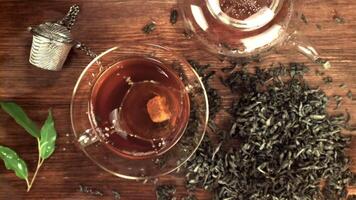 Super slow motion in a cup of tea drops sugar with splashes. On a wooden background. Top view. Filmed on a high-speed camera at 1000 fps. video