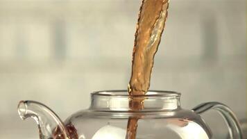 A super slow motion jet of black tea pours into the teapot. On a white background. Filmed on a high-speed camera at 1000 fps. video