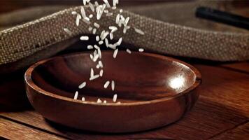 Rice is poured into a wooden bowl. Filmed on a high-speed camera at 1000 fps. High quality FullHD footage video