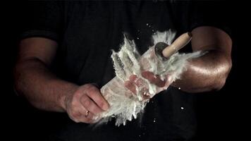 Chef with a rolling pin in his hands and flying flour. Filmed on a high-speed camera at 1000 fps. High quality FullHD footage video