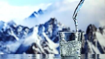 un' ruscello di acqua versa in il bicchiere nel un' idromassaggio. contro il fondale di blu montagne. girato su un' alta velocità telecamera a 1000 fps. video