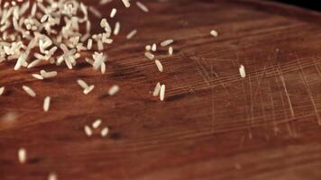 Uncooked rice is scattered on the table and rotated. On a wooden background.Filmed on a high-speed camera at 1000 fps. video