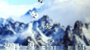 Ice cubes fall on the table and rotate in the air. Against the backdrop of snowy mountains.Filmed is slow motion 1000 fps. video