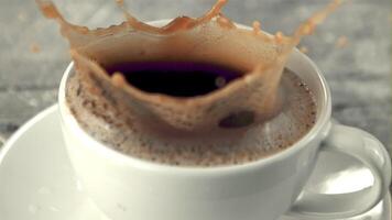 Super slow motion in a mug of coffee drops a piece of sugar with splashes. Filmed on a high-speed camera at 1000 fps.On a gray background. video