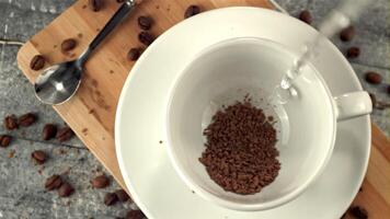 Super slow motion in a mug with instant coffee pours water. On a gray background. Filmed on a high-speed camera at 1000 fps.High quality FullHD footage video