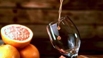 Super slow motion a jet of grapefruit juice pours into the glass. On a wooden background. Filmed on a high-speed camera at 1000 fps. video