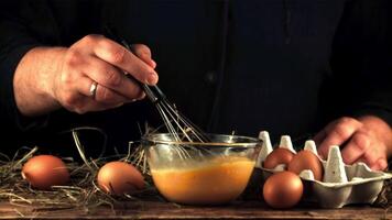 super lento movimento capocuoco prepara prima colazione di fresco uova. su un' nero sfondo. girato su un' alta velocità telecamera a 1000 fps. video