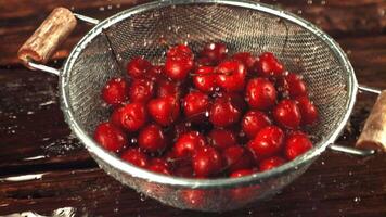 Super slow motion on the cherry in the colander drop drops of water. On a wooden background. Filmed on a high-speed camera at 1000 fps. video