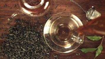 A super slow motion jet of fragrant tea pours with splashes into the cup. On a wooden background. Filmed on a high-speed camera at 1000 fps.Top view. video