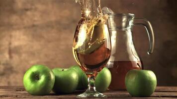 súper lento movimiento un pedazo de manzana caídas dentro un vaso de manzana jugo. en un marrón fondo.filmado en un alta velocidad cámara a 1000 fps. video