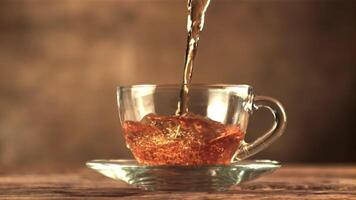 A super slow motion jet of tea pours into a cup of air bubbles. On a brown background. Filmed on a high-speed camera at 1000 fps. video