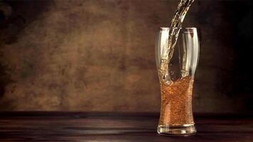 Super slow motion stream beer pours into the glass whirlpool with air bubbles. On a brown background.Filmed on a high-speed camera at 1000 fps. video