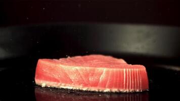 super lento movimento tonno bistecca è fritte nel un' padella con olio schizzi. su un' nero sfondo.filmato su un' alta velocità telecamera a 1000 fps. alto qualità FullHD metraggio video