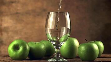 súper lento movimiento en el vaso en el mesa vierte un chorro de manzana jugo. en un marrón fondo.filmado en un alta velocidad cámara a 1000 fps. video