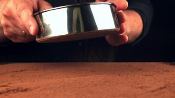 Super slow motion of the man's hand through a sieve of cocoa. On a black background. Filmed on a high-speed camera at 1000 fps. video