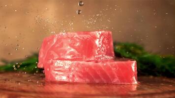 Super schleppend Bewegung auf roh Thunfisch Steaks Tropfen Wasser. auf ein braun Hintergrund. gefilmt auf ein schnelle Geschwindigkeit Kamera beim 1000 fps. video