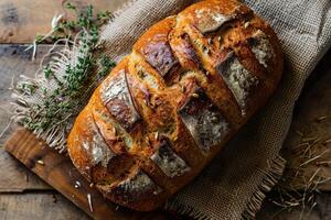 A loaf of homemade bread on a wooden table with burlap and ears of corn. View from above. photo