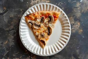 Top view of a slice of pizza with mushrooms on a paper plate. . photo