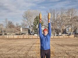 senior athletic male is exercising with wooden Indian clubs photo