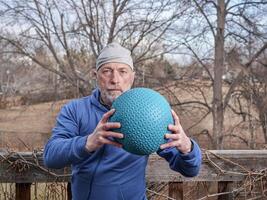 senior male is exercising with a heavy slam ball photo