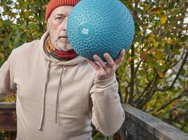 senior male is exercising with a heavy slam ball photo