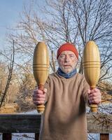 senior man is exercising with wooden Indian clubs photo