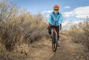 senior male cyclist is riding a gravel bike photo