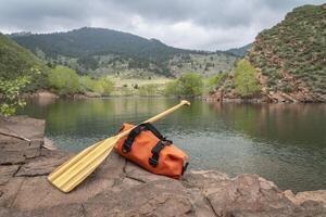 wooden canoe paddle and waterproof duffel photo