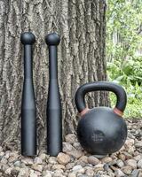 pair of heavy steel clubs and kettlebell in backyard photo