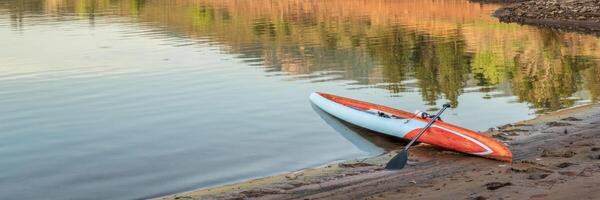 Long and narrow racing stand up paddleboard on a calm mountain lake photo