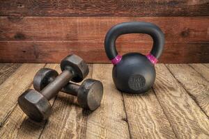 small iron kettlebell and dumbbell on a rustic wood photo