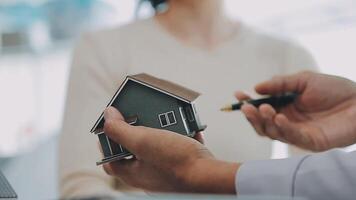 modèle de maison avec agent immobilier et client discutant d'un contrat d'achat de maison, d'assurance ou de prêt immobilier. video