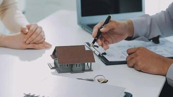 modelo de casa con agente de bienes raíces y cliente discutiendo por contrato para comprar casa, seguro o fondo de préstamo de bienes raíces. video