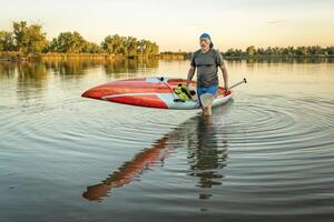 senior paddler with a racing stand up paddleboard photo