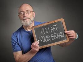 senior man with you are your brand sign photo