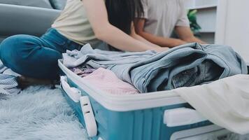 asiático mujer preparar a paquete ropa viaje lugares con su amigos. asiático hermosa dos mujer amigo paquete cosas en tu viaje bolso para Días festivos para su vacaciones viaje video