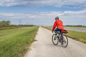 masculino ciclista es montando un grava turismo bicicleta - andar en bicicleta en un dique sendero a lo largo cadena de rocas canal cerca granito ciudad en Illinois foto