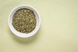 parsley dried herb - small ceramic bowl on textured paper with a copy space, top view photo