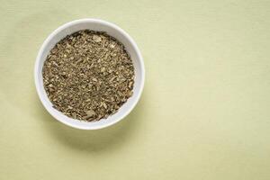 thyme dried herb - small ceramic bowl on textured paper with a copy space, top view photo