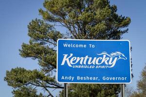 Bienvenido a Kentucky, desenfrenado espíritu - Señal de tráfico a estado frontera con Tennesse con un pino árbol en antecedentes. foto